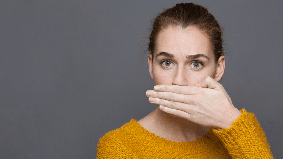 A woman covering her mouth and her eyes wide open.