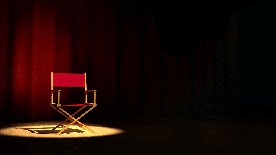 A red empty chair on stage on the spotlight.