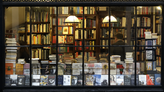 A bookstore window with rows and stacks of books inside